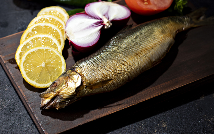 Kippers, smoked herring on a wooden board on ablack background,